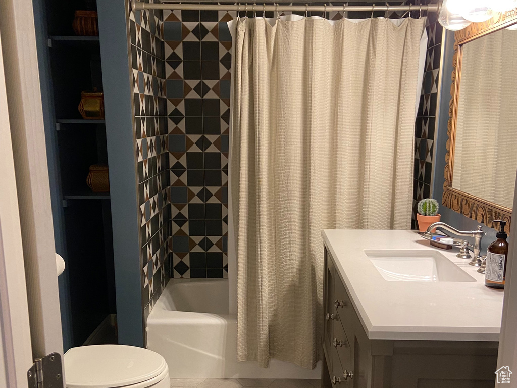 Full bathroom featuring toilet, shower / bath combination with curtain, tile floors, oversized vanity, and a textured ceiling