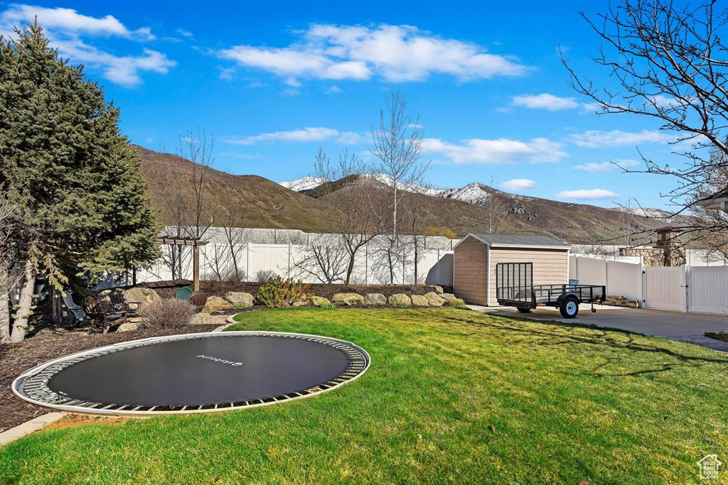 View of yard with a mountain view, a storage unit, and a trampoline