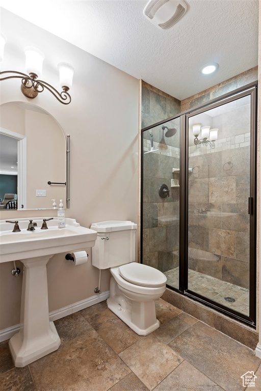 Bathroom featuring toilet, tile flooring, walk in shower, and a textured ceiling
