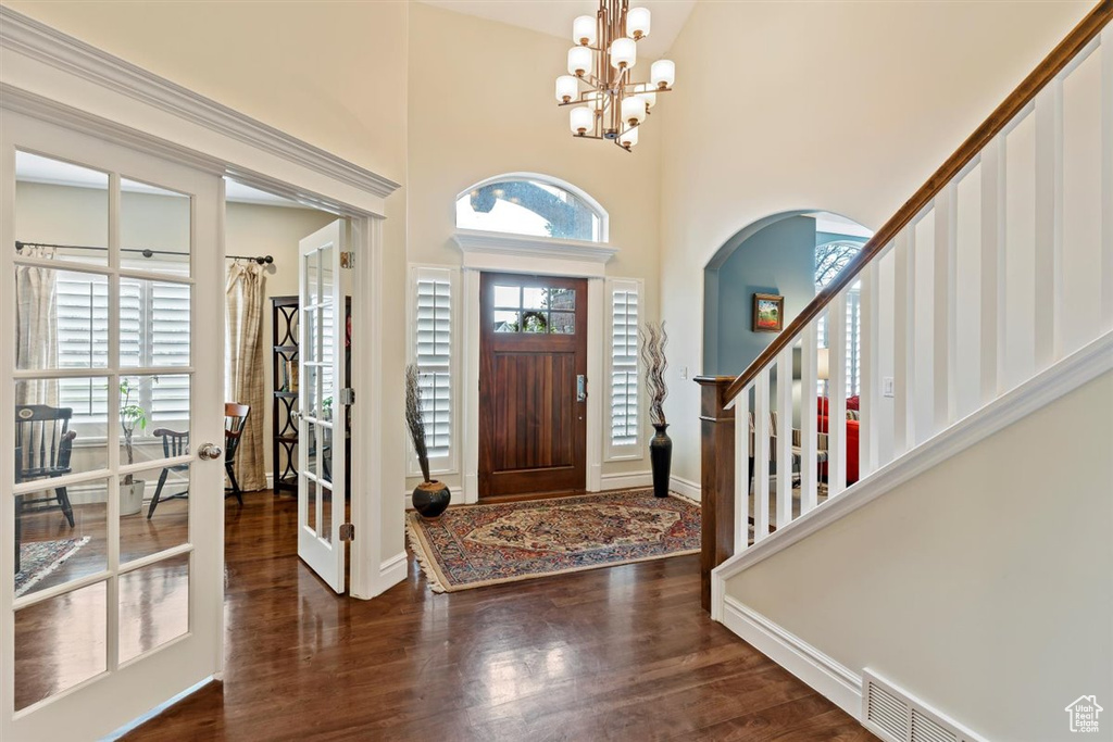 Foyer featuring an inviting chandelier, dark hardwood / wood-style floors, and a towering ceiling