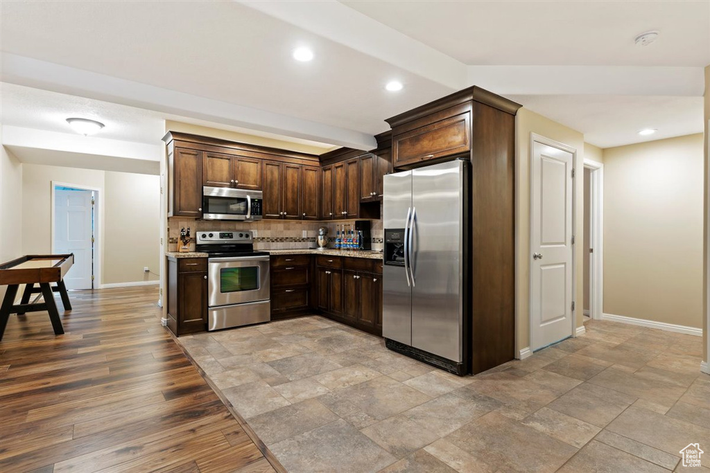 Kitchen featuring backsplash, dark brown cabinets, light hardwood / wood-style flooring, and appliances with stainless steel finishes
