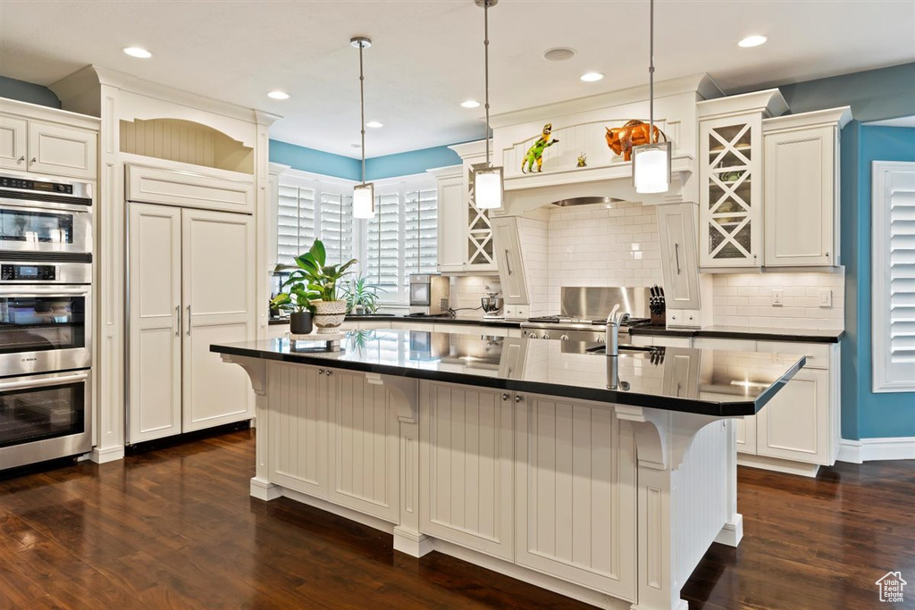Kitchen with a kitchen breakfast bar, backsplash, and dark hardwood / wood-style flooring