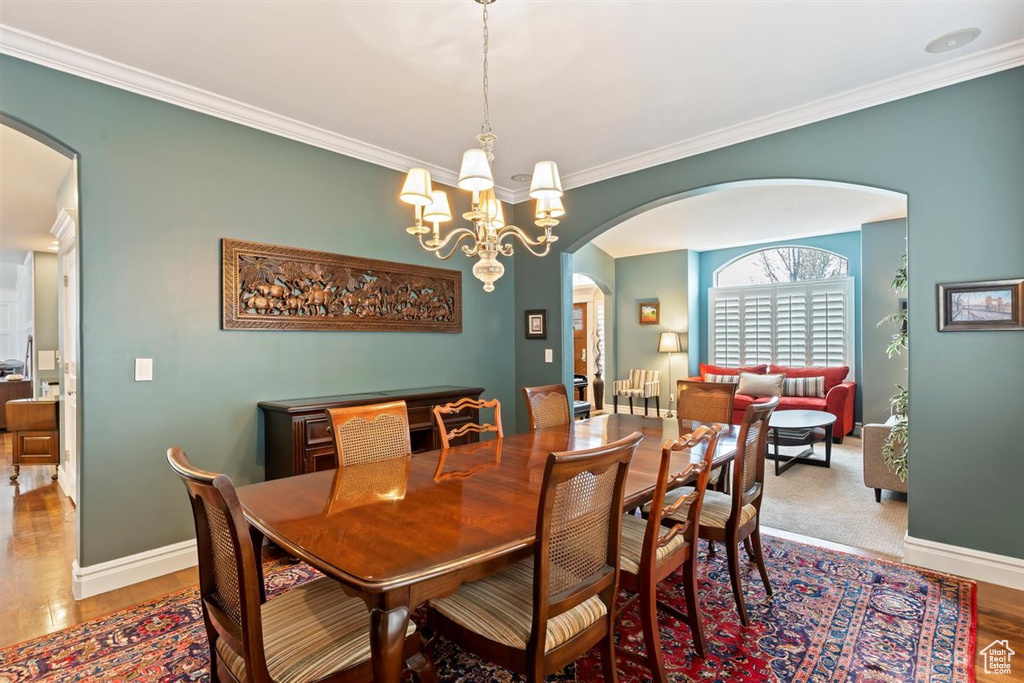 Dining room with crown molding, light wood-type flooring, and an inviting chandelier