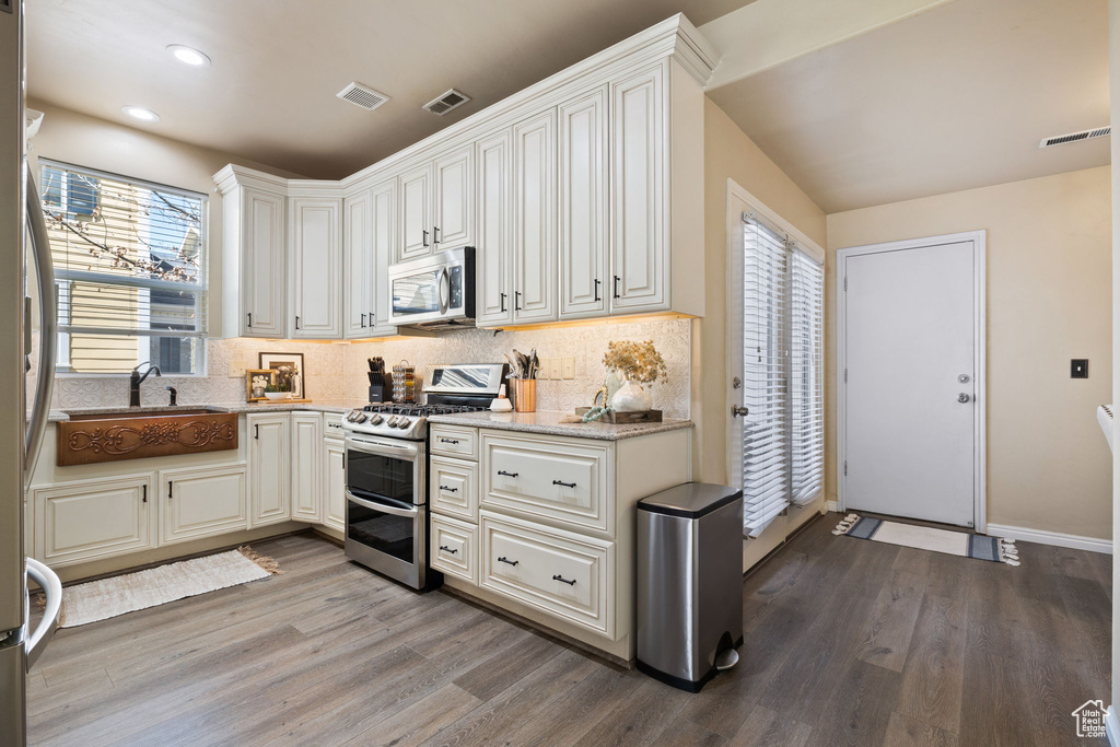 Kitchen with white cabinets, plenty of natural light, hardwood / wood-style floors, and stainless steel appliances