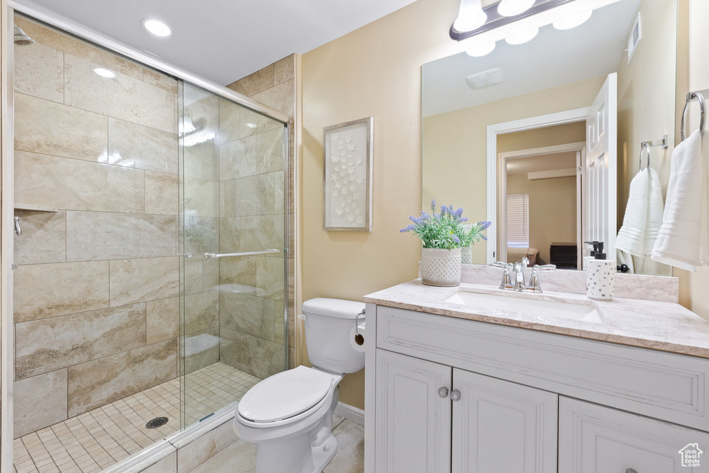 Bathroom featuring an enclosed shower, toilet, vanity with extensive cabinet space, and tile flooring