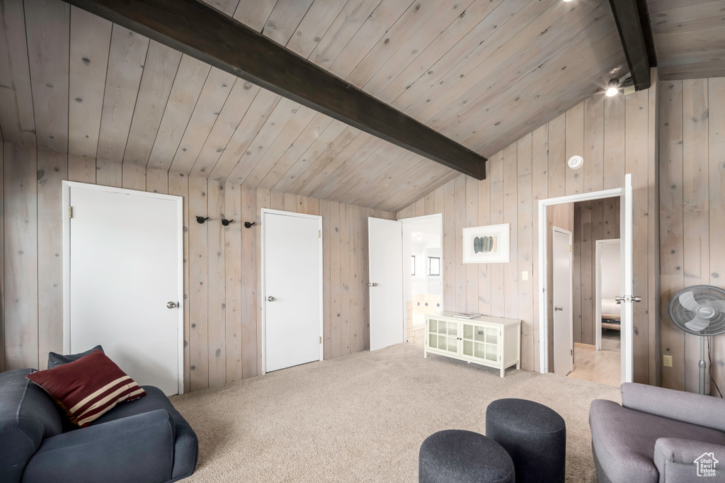 Living room with lofted ceiling with beams, wood ceiling, wooden walls, and carpet