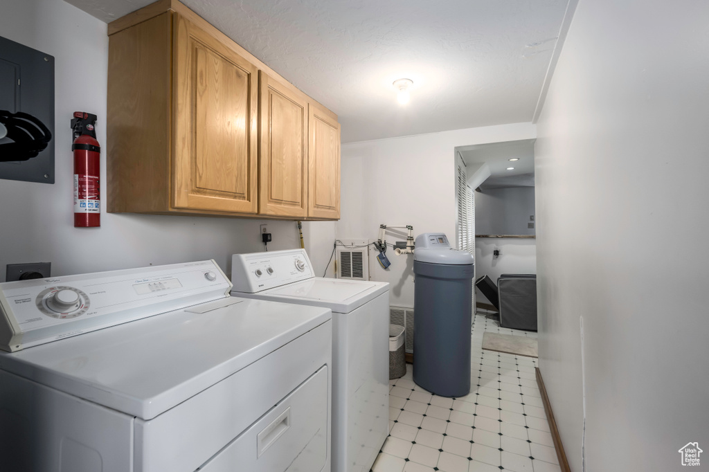 Laundry area with hookup for an electric dryer, cabinets, independent washer and dryer, and light tile floors