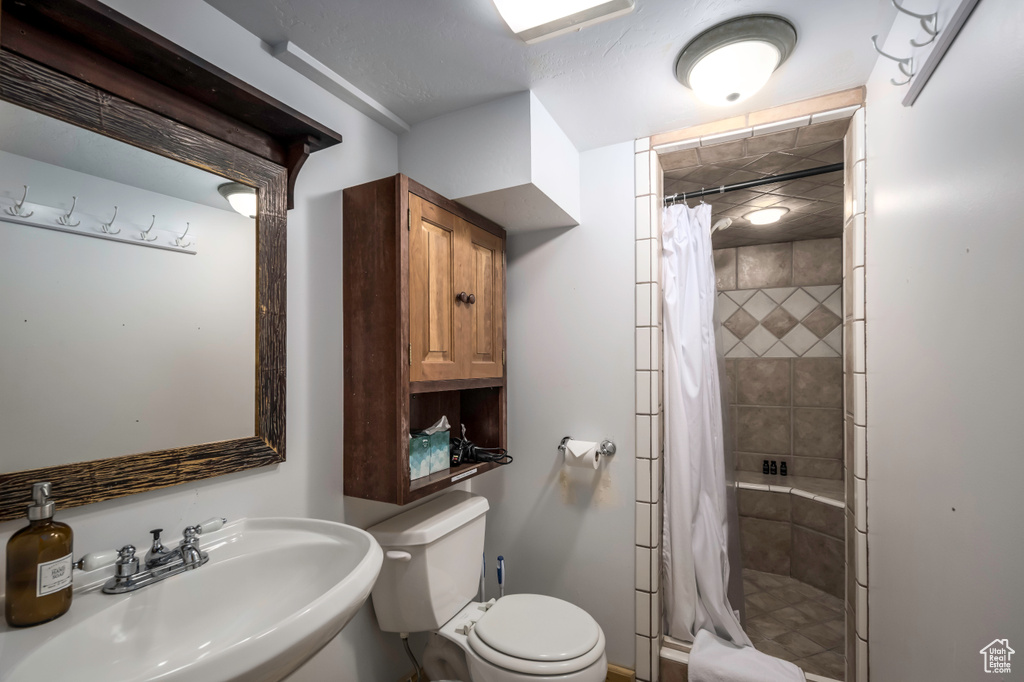 Bathroom featuring toilet, a shower with shower curtain, and sink