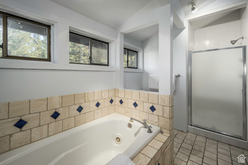Bathroom with lofted ceiling, tile flooring, and plus walk in shower
