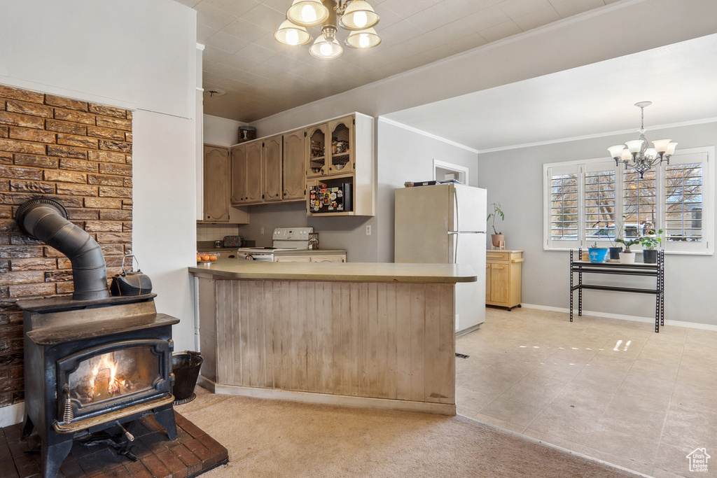 Kitchen featuring white appliances, a wood stove, light carpet, decorative light fixtures, and a notable chandelier