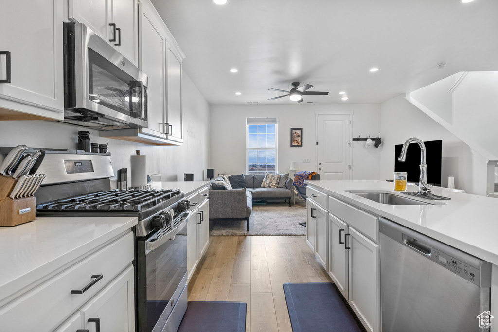 Kitchen with white cabinetry, ceiling fan, sink, light hardwood / wood-style flooring, and stainless steel appliances