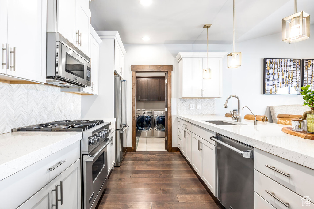 Kitchen featuring hanging light fixtures, tasteful backsplash, stainless steel appliances, and dark wood-type flooring