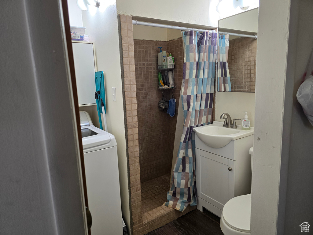 Bathroom with curtained shower, toilet, vanity, and washer / dryer