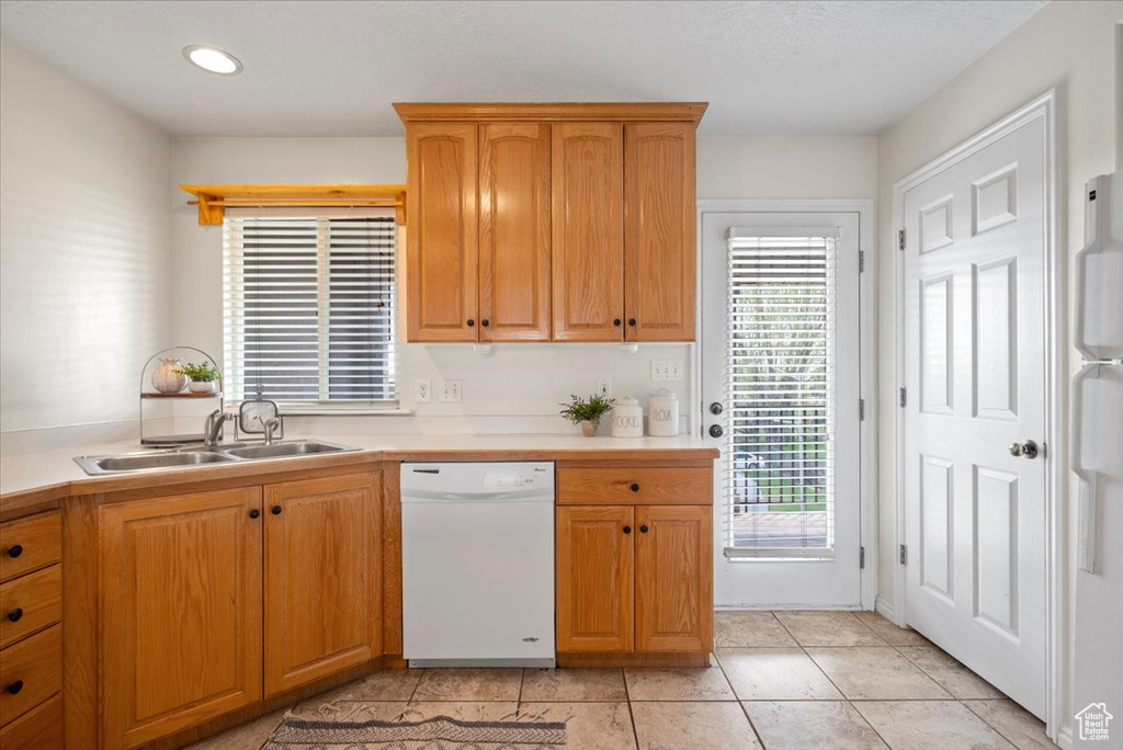 Kitchen featuring a healthy amount of sunlight, white dishwasher, sink, and light tile flooring