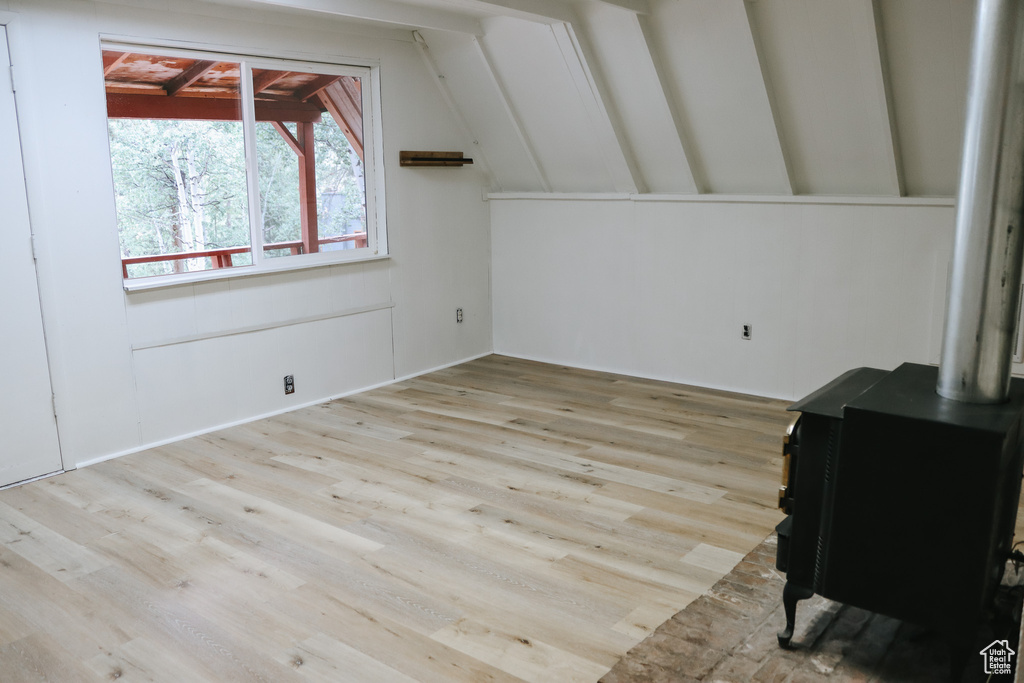 Bonus room featuring lofted ceiling, a wood stove, and light hardwood / wood-style flooring