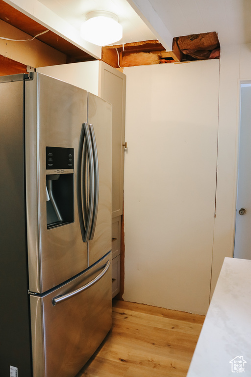 Kitchen with white cabinets, light hardwood / wood-style floors, and stainless steel refrigerator with ice dispenser