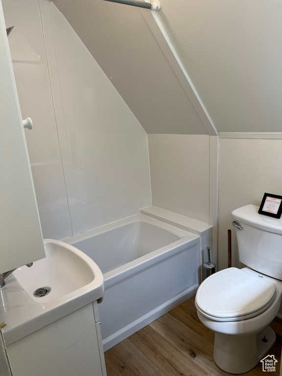 Bathroom with vanity, lofted ceiling, wood-type flooring, and toilet