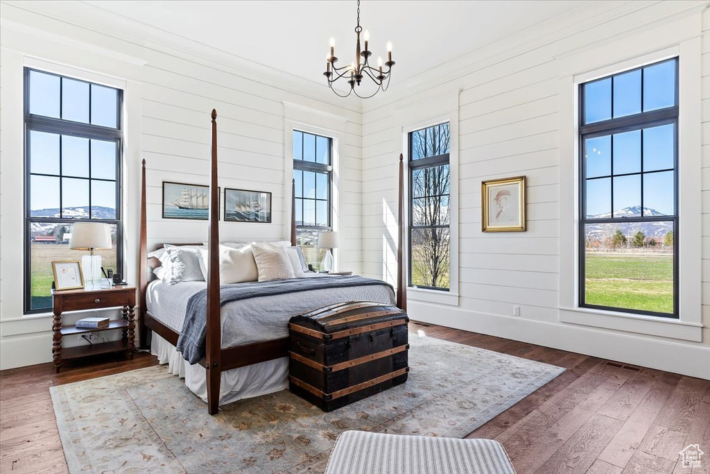 Bedroom with an inviting chandelier, hardwood / wood-style floors, and multiple windows