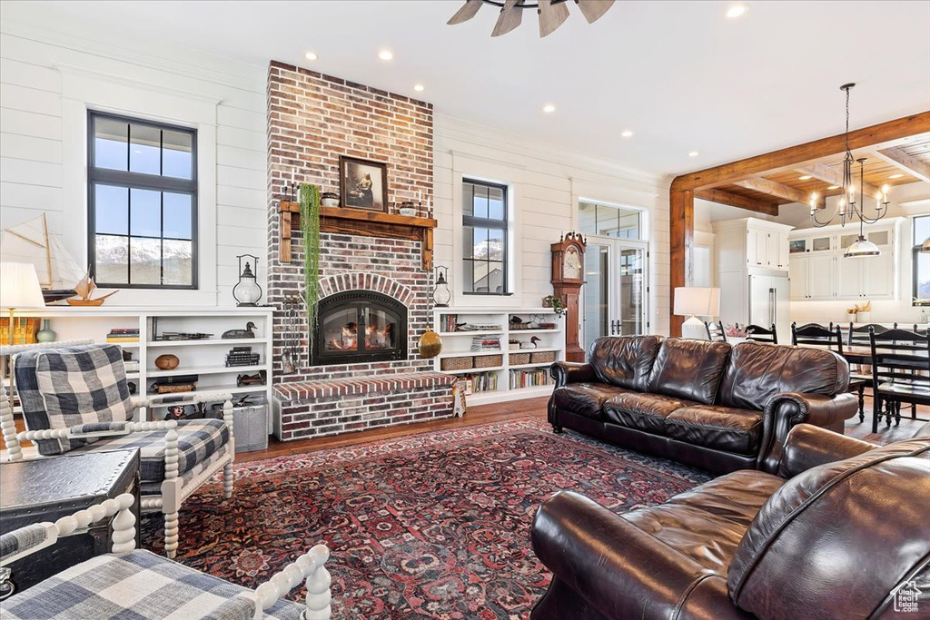 Living room featuring hardwood / wood-style floors, beamed ceiling, plenty of natural light, and a brick fireplace