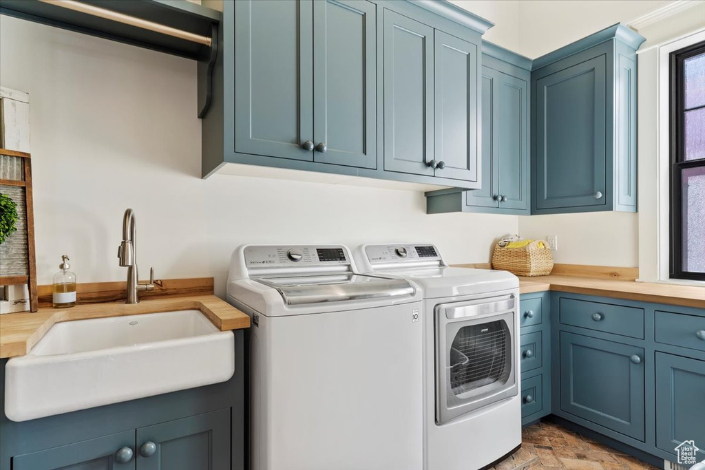 Laundry room with washing machine and clothes dryer, cabinets, and sink