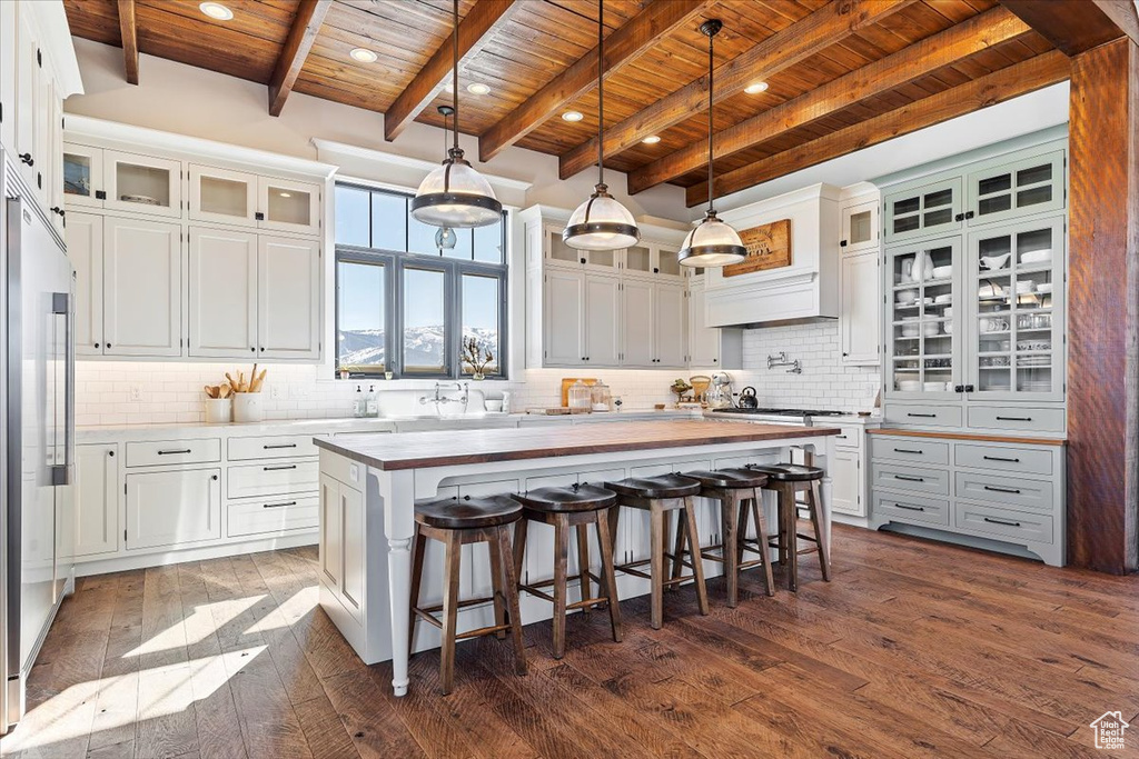 Kitchen featuring tasteful backsplash, wooden ceiling, a kitchen island, and white cabinetry