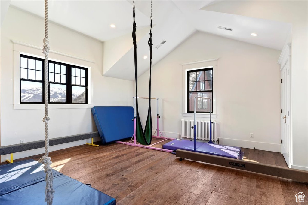 Exercise area featuring lofted ceiling, radiator, and dark hardwood / wood-style flooring