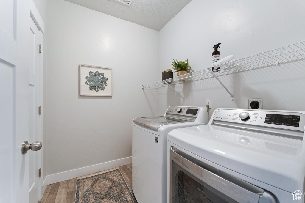 Laundry room with washer and dryer, electric dryer hookup, and light hardwood / wood-style floors