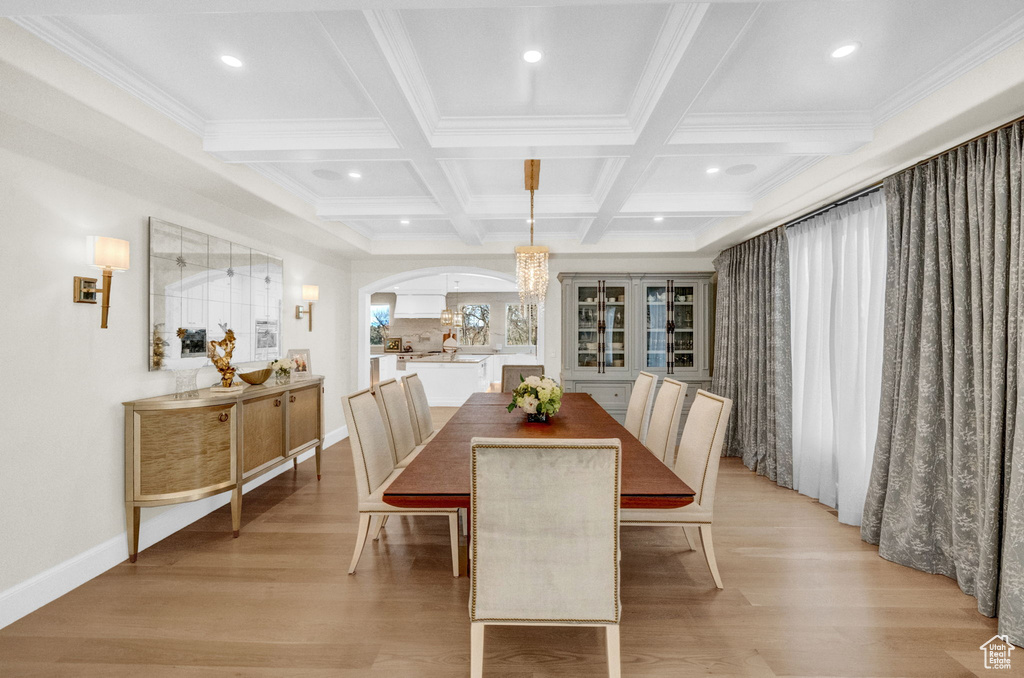 Dining area featuring coffered ceiling, light hardwood / wood-style floors, a notable chandelier, and beam ceiling