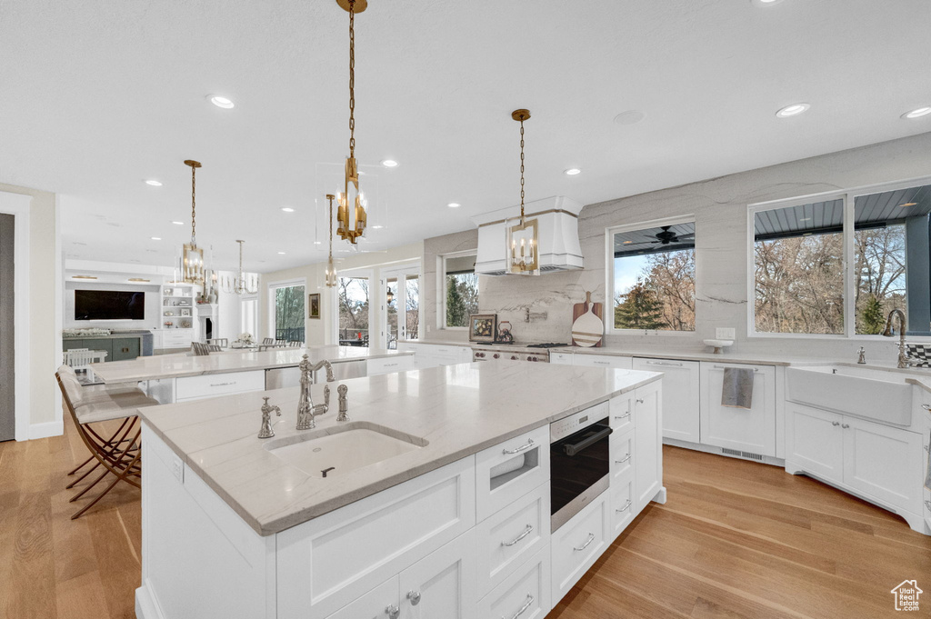 Kitchen with white cabinets, pendant lighting, and a kitchen island with sink