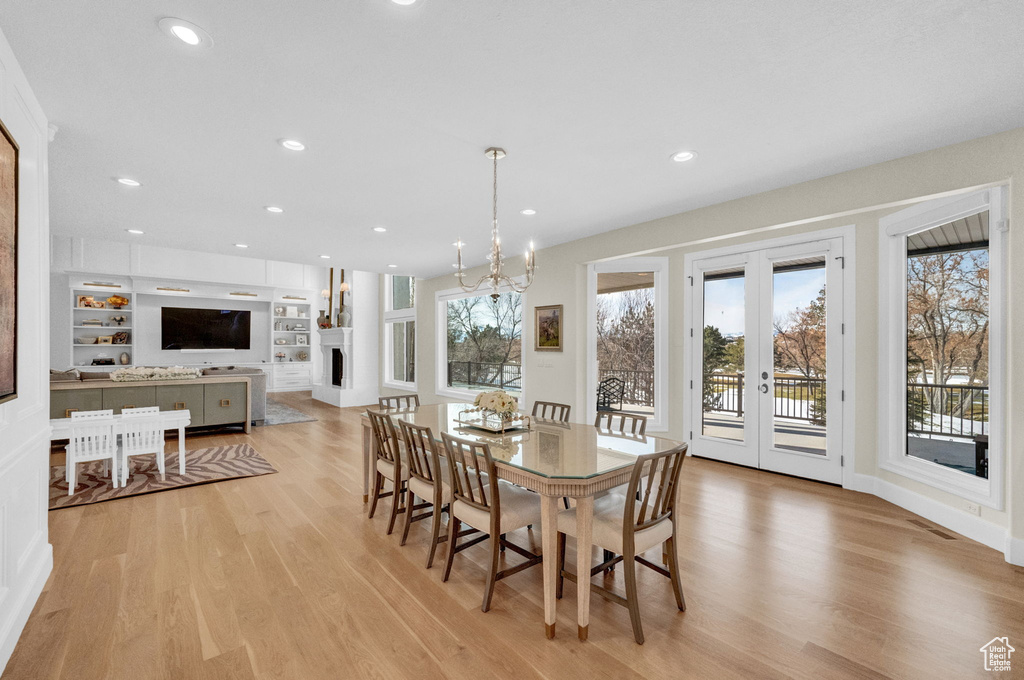 Dining space featuring built in features, a notable chandelier, french doors, and light hardwood / wood-style flooring