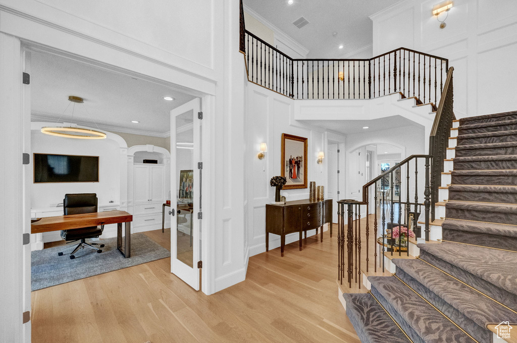 Staircase featuring light hardwood / wood-style floors, a high ceiling, and crown molding