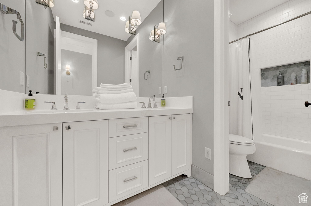 Full bathroom with toilet, double sink, vanity with extensive cabinet space, shower / tub combo with curtain, and tile flooring