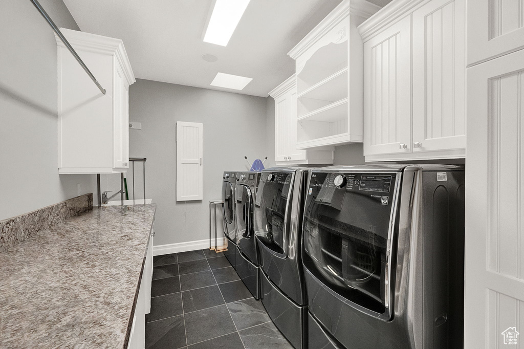 Washroom with separate washer and dryer, cabinets, and dark tile floors
