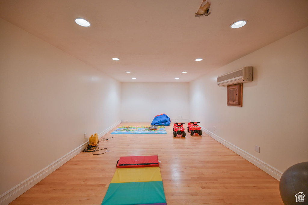 Rec room with a wall mounted air conditioner and hardwood / wood-style flooring
