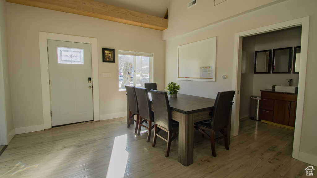 Dining space featuring light hardwood / wood-style floors, sink, and beamed ceiling