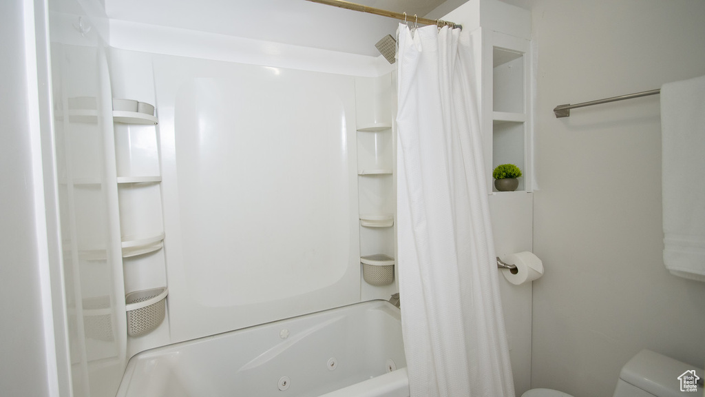 Bathroom with toilet and shower / tub combo with curtain