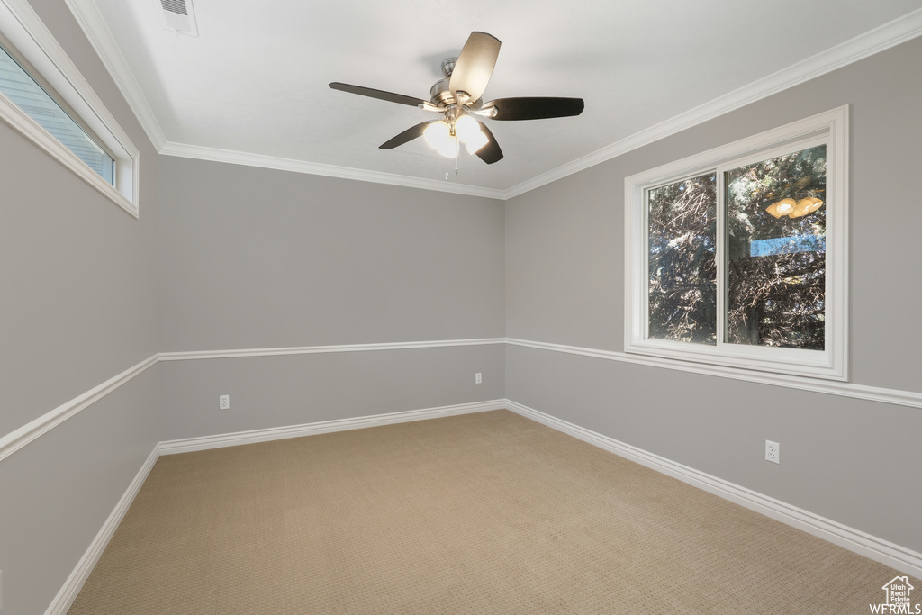 Empty room with light carpet, crown molding, and ceiling fan