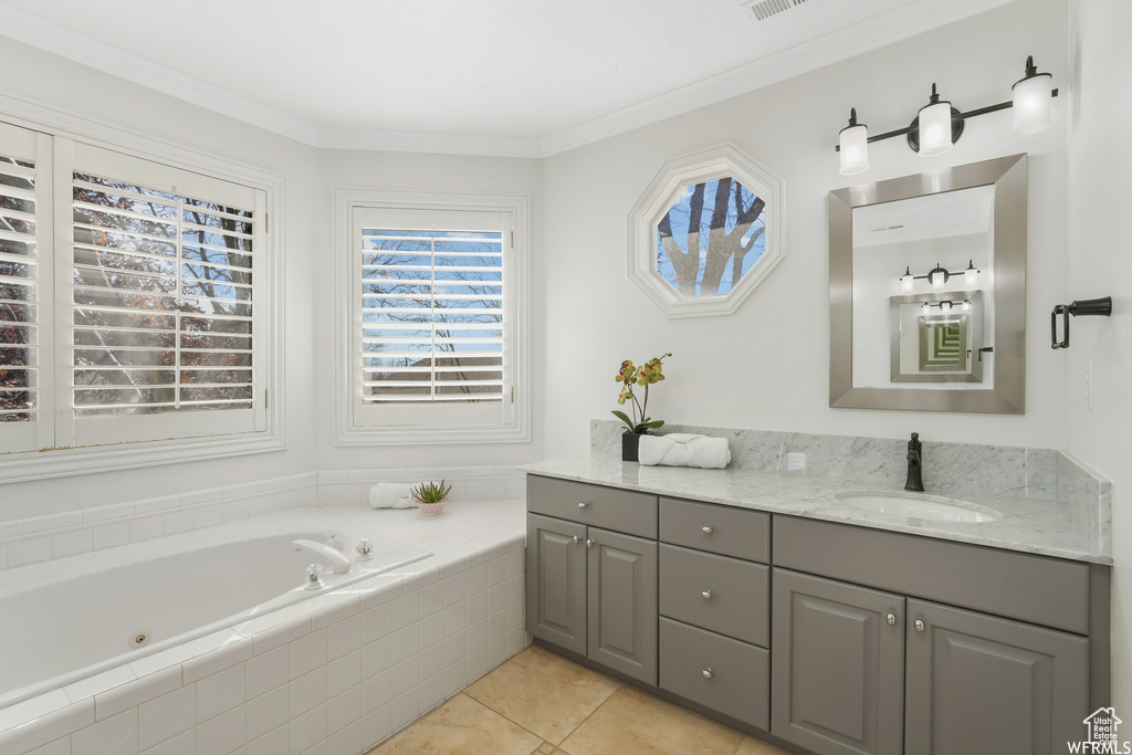 Bathroom featuring vanity, tile floors, crown molding, and tiled tub