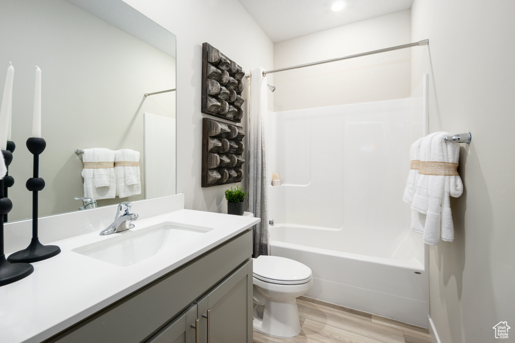 Full bathroom featuring vanity,  shower combination, hardwood / wood-style floors, and toilet