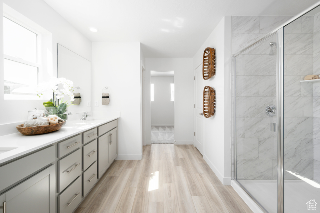 Bathroom featuring plenty of natural light, double vanity, a shower with door, and hardwood / wood-style flooring