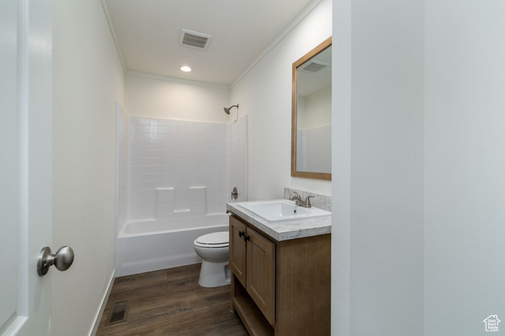Full bathroom featuring toilet, bathtub / shower combination, hardwood / wood-style flooring, vanity, and crown molding