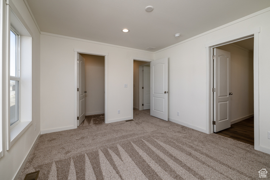 Unfurnished bedroom with crown molding, a closet, and hardwood / wood-style flooring