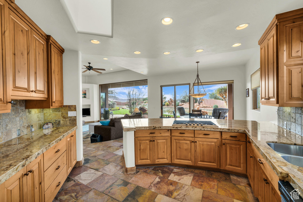 Kitchen with pendant lighting, ceiling fan, dark tile flooring, dishwashing machine, and backsplash