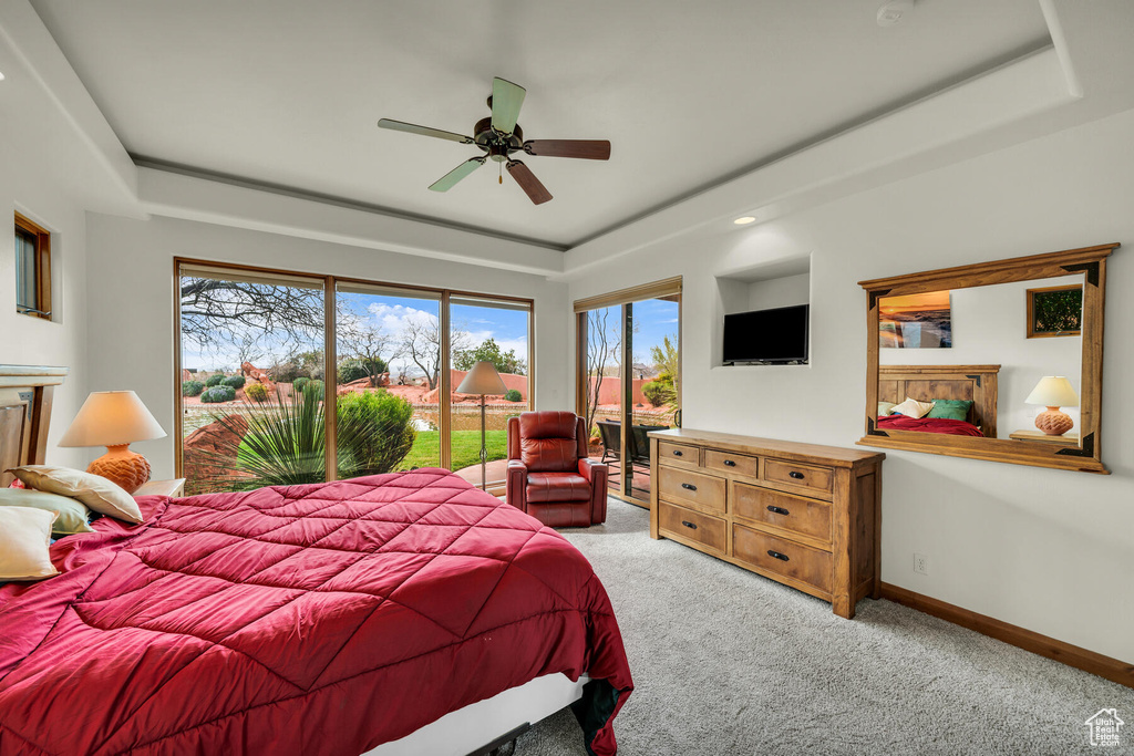 Bedroom with ceiling fan, a tray ceiling, access to exterior, and light colored carpet