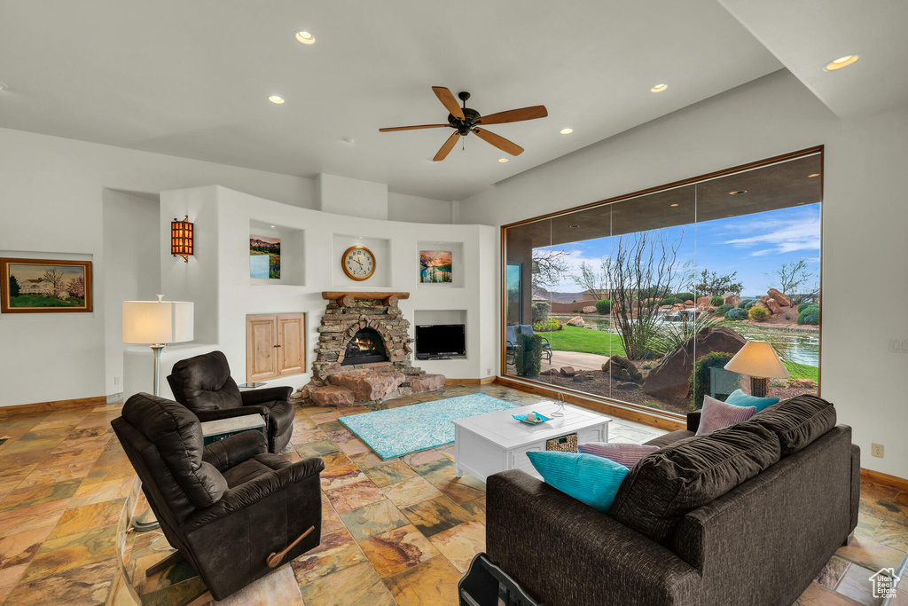 Living room featuring light tile floors, ceiling fan, and a fireplace