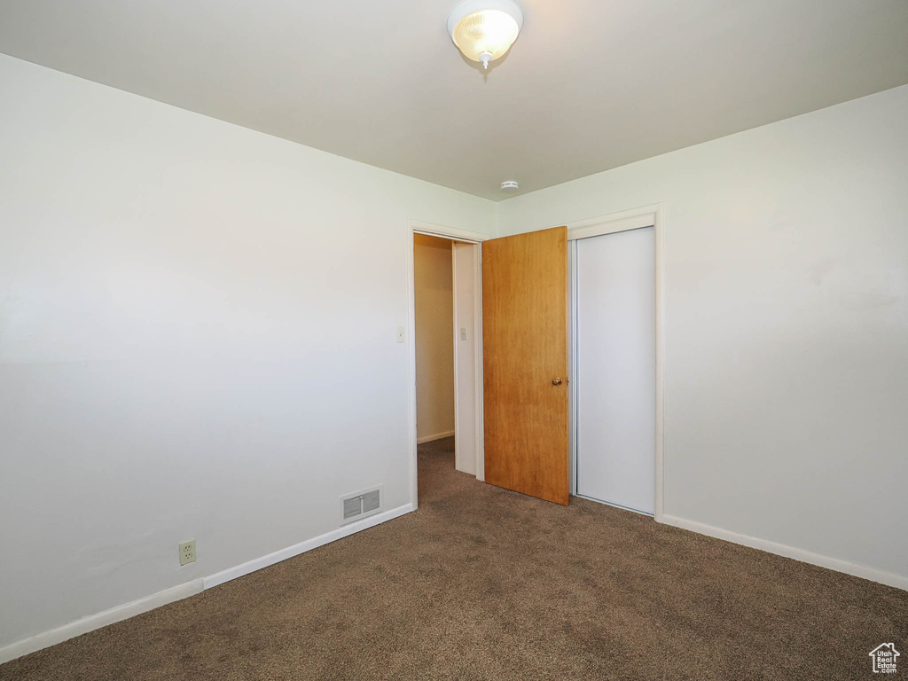 Unfurnished bedroom with a closet and dark carpet