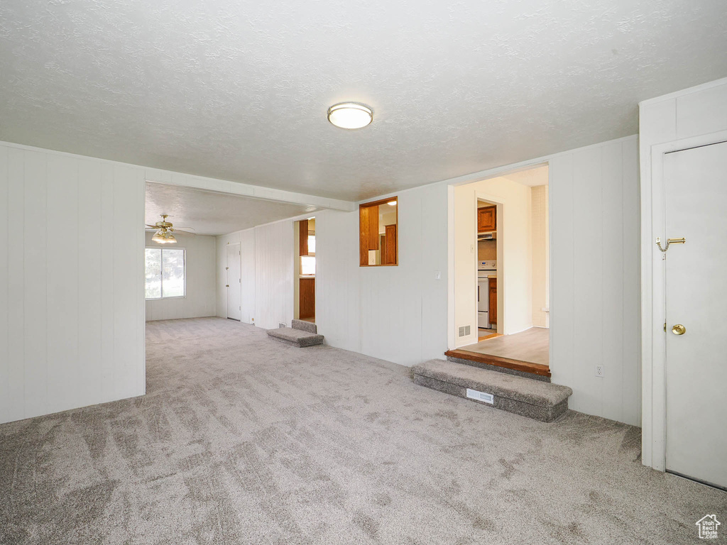 Interior space with light colored carpet, ceiling fan, and a textured ceiling