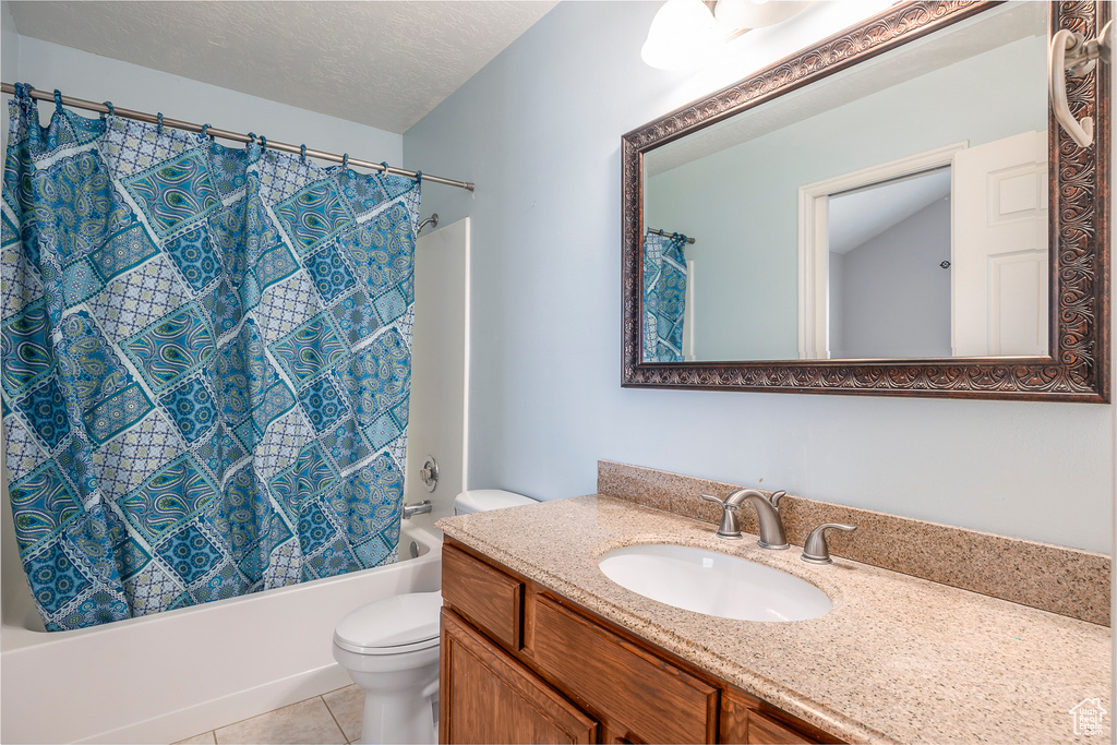 Full bathroom featuring vanity, shower / bath combo, a textured ceiling, tile flooring, and toilet