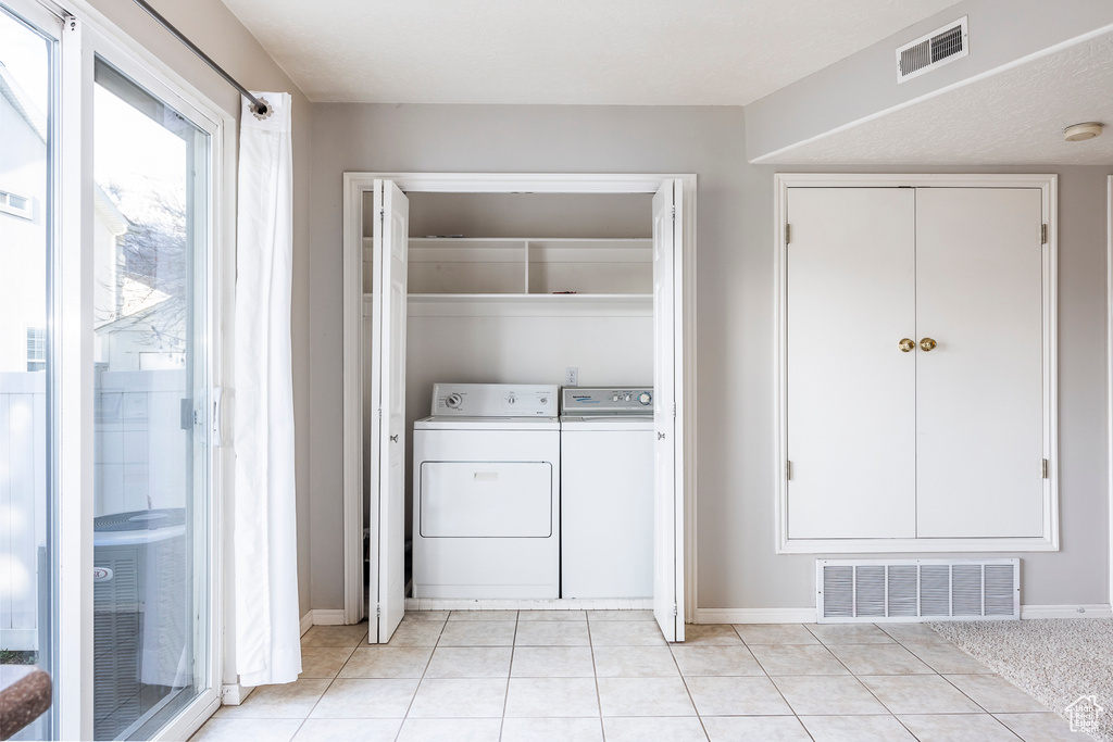 Laundry room featuring washer and dryer and light tile flooring