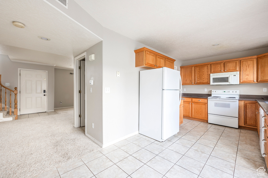 Kitchen with white appliances and light colored carpet